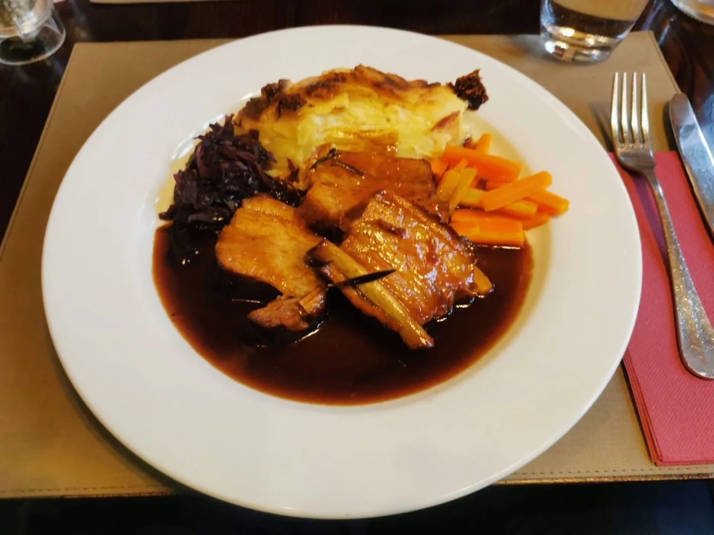 Une assiette de viande en sauce, gratin et carottes