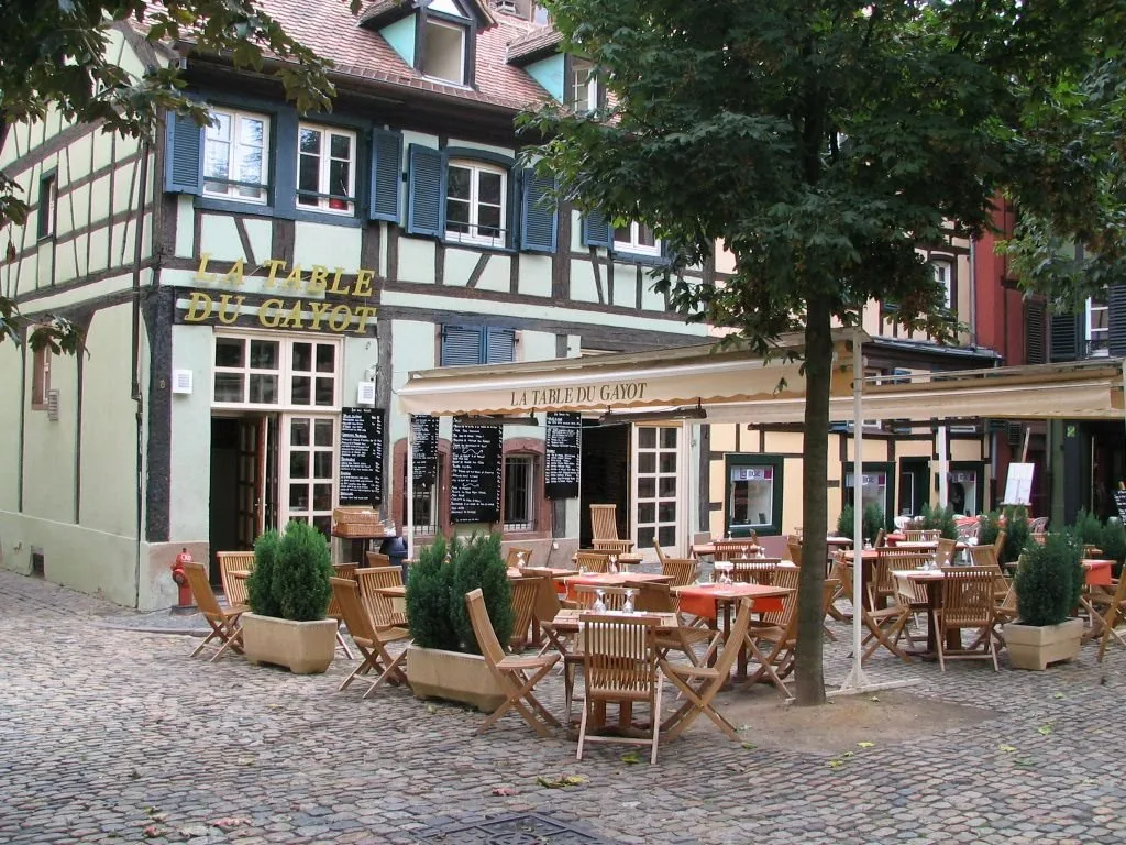 La terrasse sur la place pavée, sous les arbres